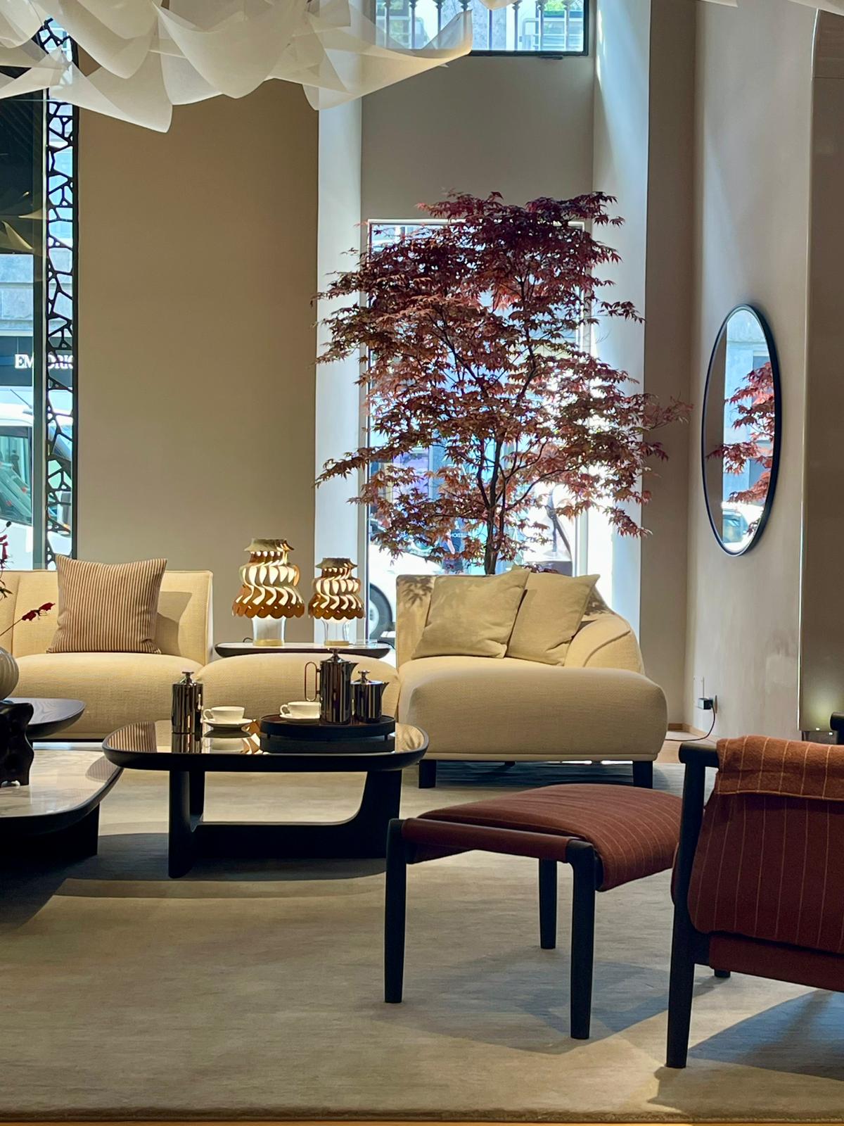 Poltrona Frau Wohnwelt mit Sesseln, Sofa, Beistelltischen und warmer Lichtstimmung im Flagshipstore Mailand